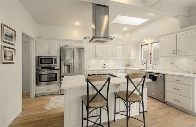 12600 Mohawk Ln, Leawood, KS 66209 - kitchen with stainless steel appliances, island exhaust hood, a skylight, decorative backsplash, and white cabinetry