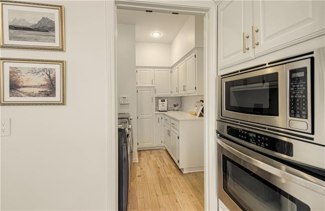 12600 Mohawk Ln, Leawood, KS 66209 - kitchen featuring stainless steel appliances, light wood finished floors, white cabinetry, washing machine and clothes dryer, and light countertops