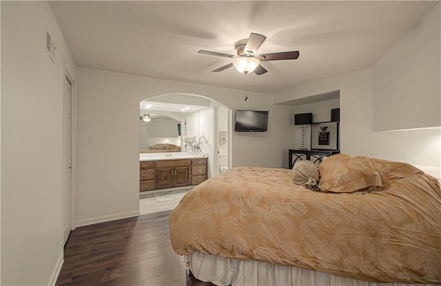 12600 Mohawk Ln, Leawood, KS 66209 - bedroom with arched walkways, dark wood-style floors, connected bathroom, and a ceiling fan