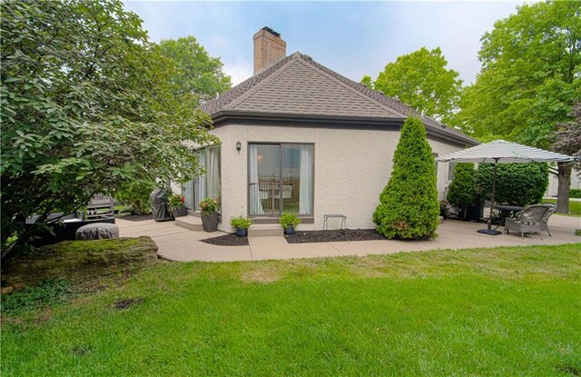 12600 Mohawk Ln, Leawood, KS 66209 - rear view of property featuring stucco siding, a lawn, a chimney, roof with shingles, and a patio area