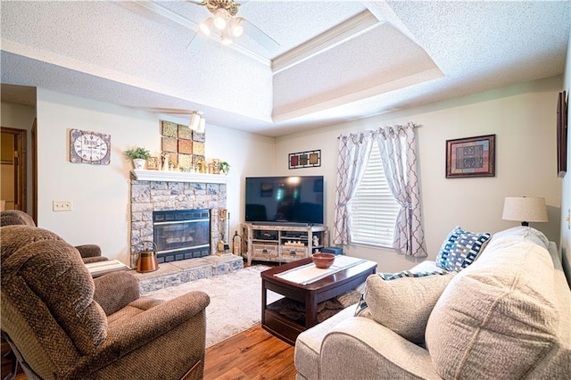 203 Scout St, Camden Point, MO 64018 - living room with wood finished floors, ceiling fan, a stone fireplace, a tray ceiling, and a textured ceiling