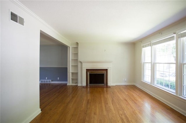 7236 Roe Ave, Prairie Village, KS 66208 - unfurnished living room with wood finished floors, a brick fireplace, crown molding, and built in shelves