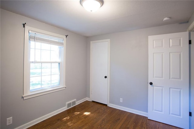 7236 Roe Ave, Prairie Village, KS 66208 - unfurnished bedroom with multiple windows, dark wood-style floors, and a closet