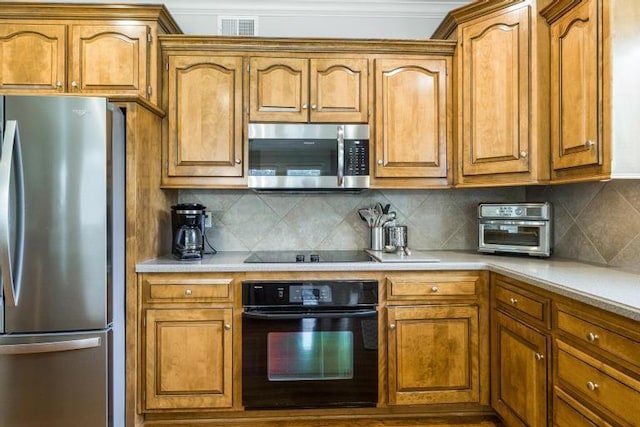 5125 W 164th St, Overland Park, KS 66085 - kitchen featuring black appliances, light countertops, brown cabinetry, and decorative backsplash
