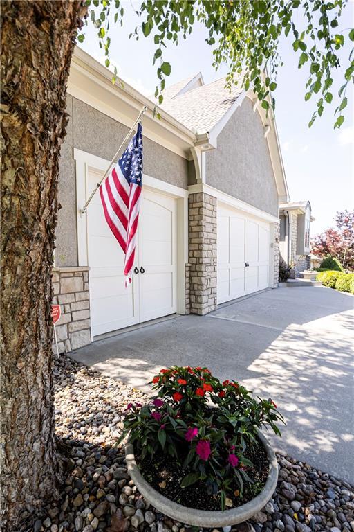 4500 Parks Summit Ter, Lees Summit, MO 64064 - view of side of home with stone siding, stucco siding, a garage, and driveway