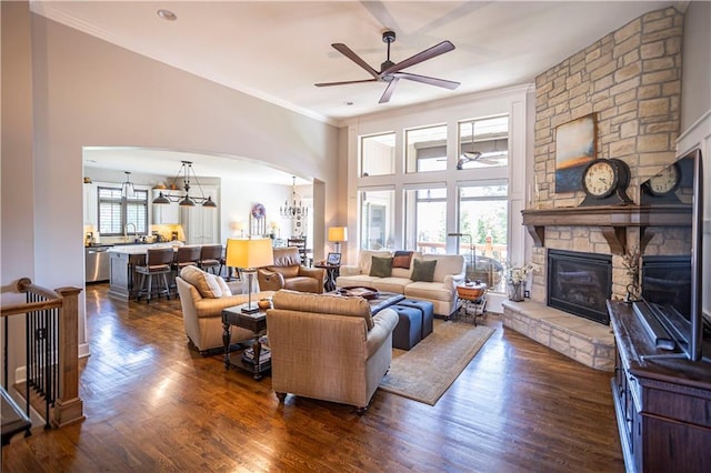 4500 Parks Summit Ter, Lees Summit, MO 64064 - living room featuring ceiling fan, arched walkways, a stone fireplace, crown molding, and dark wood-type flooring