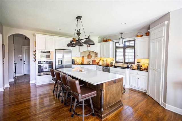 4500 Parks Summit Ter, Lees Summit, MO 64064 - kitchen with appliances with stainless steel finishes, arched walkways, dark wood finished floors, tasteful backsplash, and a center island