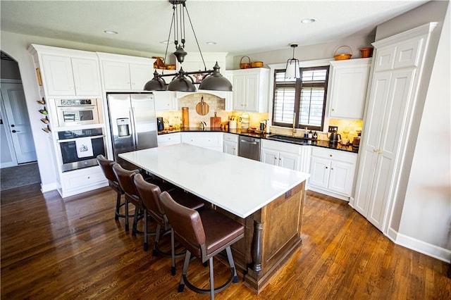 4500 Parks Summit Ter, Lees Summit, MO 64064 - kitchen with appliances with stainless steel finishes, backsplash, a kitchen island, dark wood-style flooring, and recessed lighting