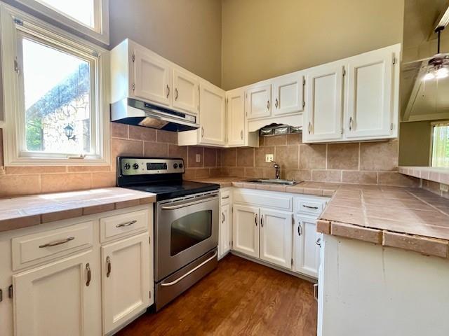 6960 Dancaster Rd, Topeka, KS 66610 - kitchen featuring under cabinet range hood, electric range, tile countertops, and white cabinets