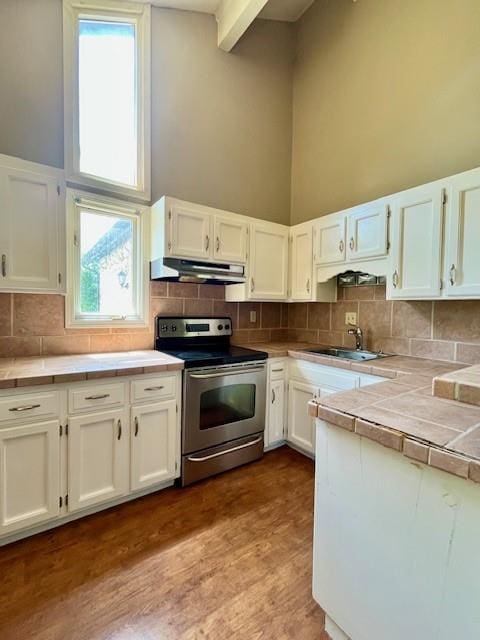 6960 Dancaster Rd, Topeka, KS 66610 - kitchen with electric range, a high ceiling, tile countertops, white cabinets, and under cabinet range hood