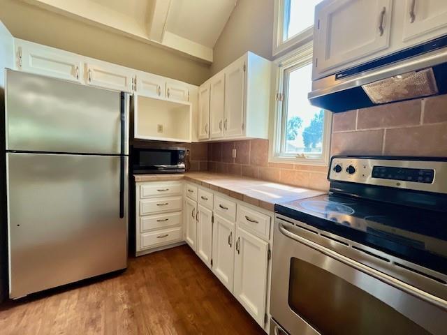 6960 Dancaster Rd, Topeka, KS 66610 - kitchen with stainless steel appliances, white cabinetry, dark wood-style flooring, under cabinet range hood, and lofted ceiling