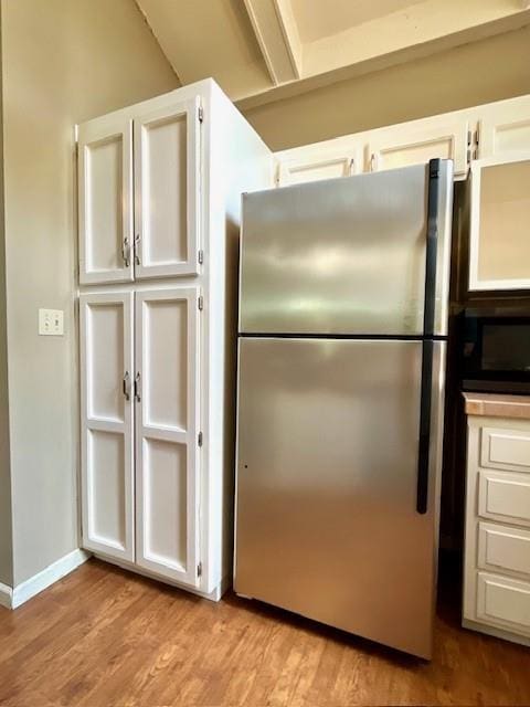 6960 Dancaster Rd, Topeka, KS 66610 - kitchen with freestanding refrigerator, black microwave, light wood-style flooring, and white cabinetry