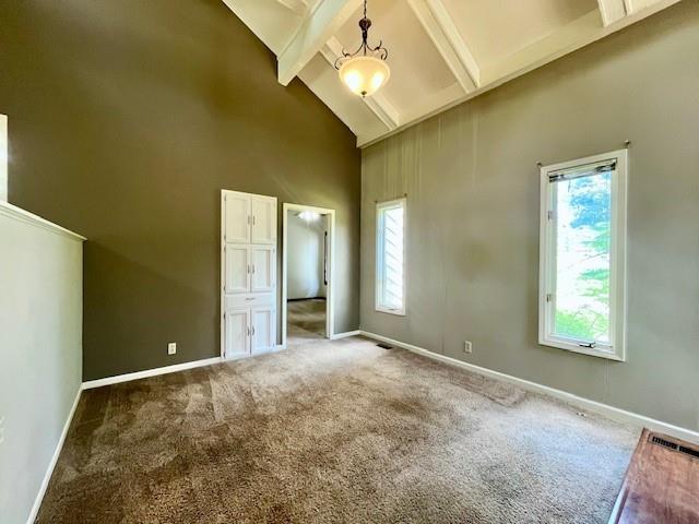 6960 Dancaster Rd, Topeka, KS 66610 - unfurnished bedroom featuring high vaulted ceiling, multiple windows, beamed ceiling, and carpet floors