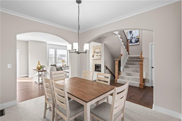 28225 W 162nd Ter, Gardner, KS 66030 - dining space featuring a fireplace, stairs, ornamental molding, a chandelier, and arched walkways