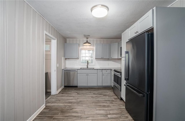 914 Jersey St, Baldwin City, KS 66006 - kitchen with appliances with stainless steel finishes, a textured ceiling, wood finished floors, and decorative light fixtures