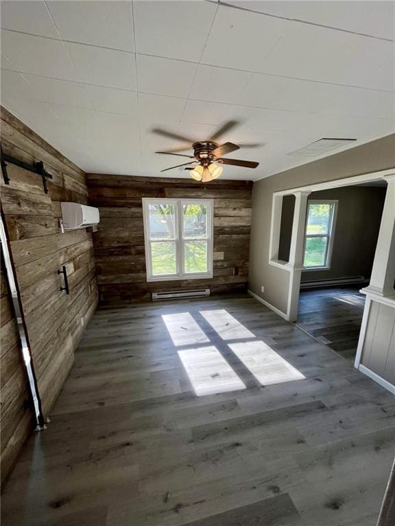 1629 E Oak St, Fort Scott, KS 66701 - unfurnished room with baseboard heating, wood walls, ceiling fan, dark wood-style floors, and a wall mounted AC