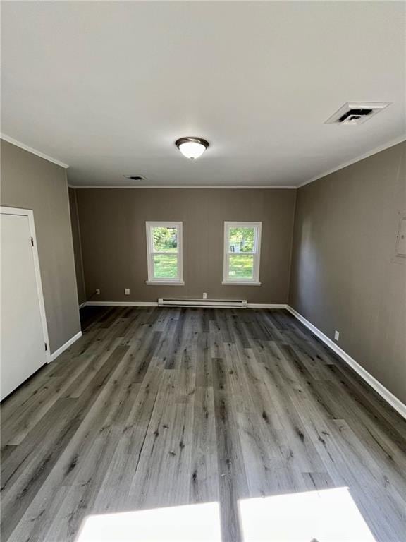 1629 E Oak St, Fort Scott, KS 66701 - empty room featuring ornamental molding, wood finished floors, and a baseboard heating unit