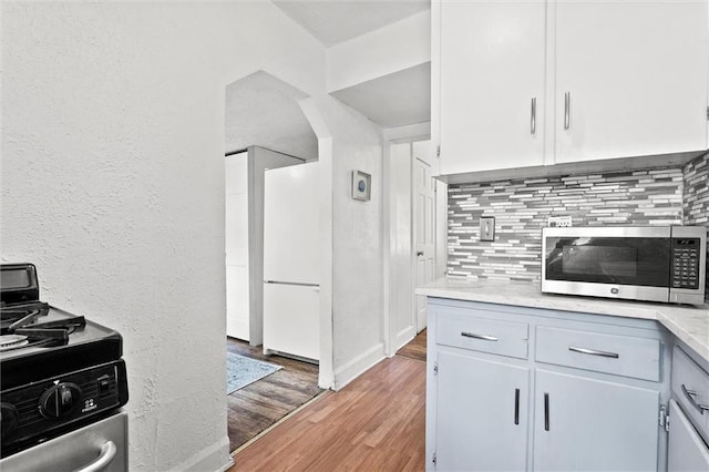 707 W 75th Ter, Kansas City, MO 64114 - kitchen with stainless steel appliances, backsplash, light wood-style floors, light countertops, and a textured wall