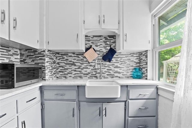 707 W 75th Ter, Kansas City, MO 64114 - kitchen featuring stainless steel microwave, gray cabinetry, and backsplash