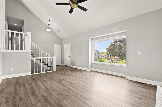 1108 W Pleasant Dr, Raymore, MO 64083 - unfurnished living room with ceiling fan, high vaulted ceiling, wood finished floors, and stairs