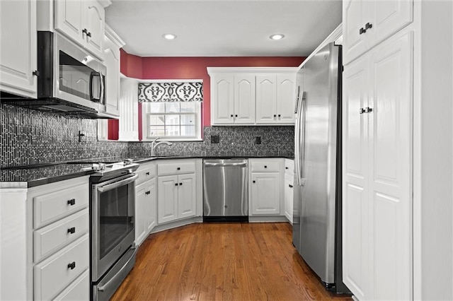 1002 W Howard Pl, Louisburg, KS 66053 - kitchen with stainless steel appliances, dark countertops, white cabinets, backsplash, and recessed lighting
