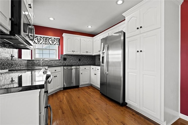 1002 W Howard Pl, Louisburg, KS 66053 - kitchen with appliances with stainless steel finishes, dark countertops, white cabinetry, dark wood-style flooring, and tasteful backsplash