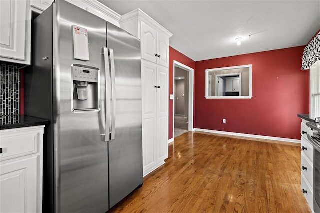 1002 W Howard Pl, Louisburg, KS 66053 - kitchen with stainless steel fridge, white cabinets, dark countertops, and light wood finished floors