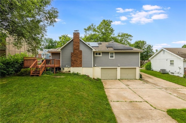 6613 E 123rd Ter, Grandview, MO 64030 - back of house featuring a lawn, a garage, solar panels, and a wooden deck