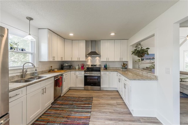 6613 E 123rd Ter, Grandview, MO 64030 - kitchen featuring stainless steel appliances, wall chimney range hood, light wood-style floors, white cabinets, and a textured ceiling