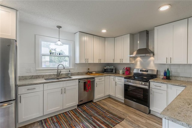 6613 E 123rd Ter, Grandview, MO 64030 - kitchen featuring stainless steel appliances, wall chimney range hood, light wood-type flooring, white cabinets, and a textured ceiling
