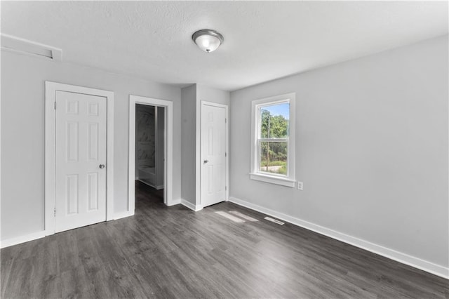 1205 E Parker Ave, Independence, MO 64050 - unfurnished bedroom featuring dark wood-style floors and a textured ceiling