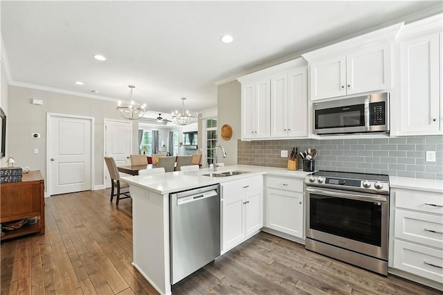 704 E 110th Ter, Kansas City, MO 64131 - kitchen featuring stainless steel appliances, a chandelier, a peninsula, crown molding, and white cabinets