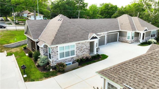 704 E 110th Ter, Kansas City, MO 64131 - single story home with stone siding, a garage, concrete driveway, and roof with shingles