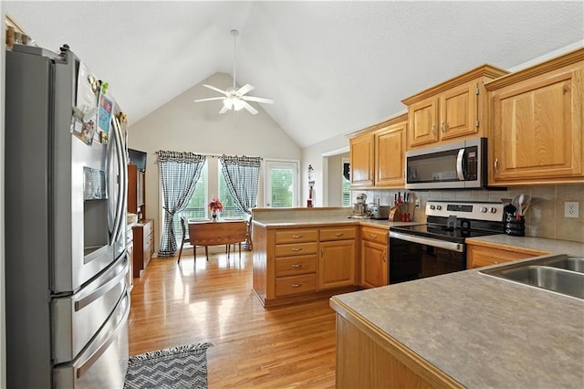 2353 SW Switchback Ct, Lees Summit, MO 64082 - kitchen featuring appliances with stainless steel finishes, a peninsula, ceiling fan, high vaulted ceiling, and light wood-style floors