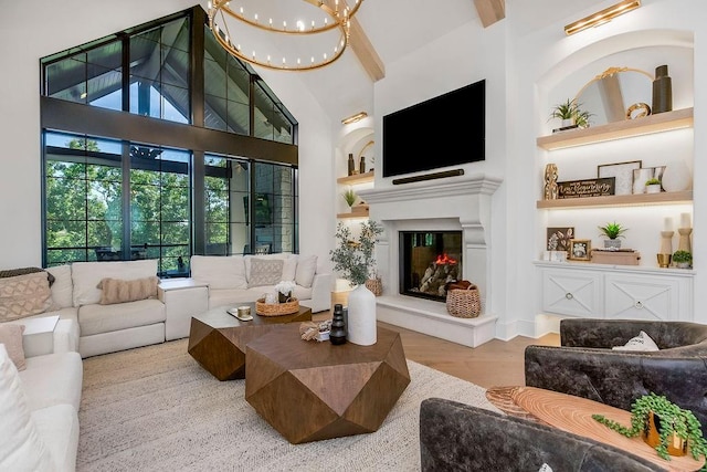 27497 W 108th St, Olathe, KS 66061 - living room with a chandelier, built in features, a glass covered fireplace, a high ceiling, and wood finished floors