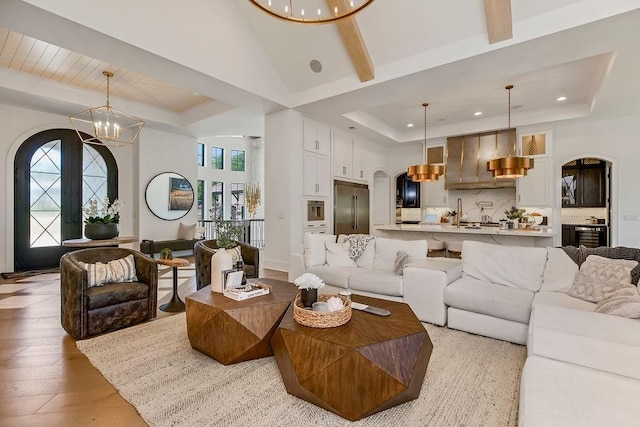 27497 W 108th St, Olathe, KS 66061 - living room with a chandelier, a towering ceiling, arched walkways, plenty of natural light, and light wood-type flooring