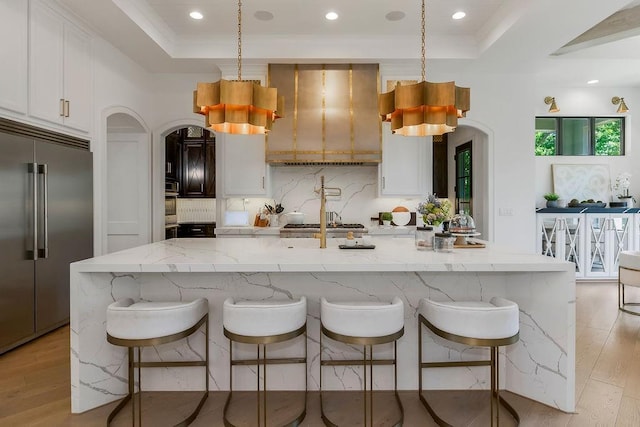 27497 W 108th St, Olathe, KS 66061 - kitchen with appliances with stainless steel finishes, arched walkways, a raised ceiling, wall chimney range hood, and recessed lighting
