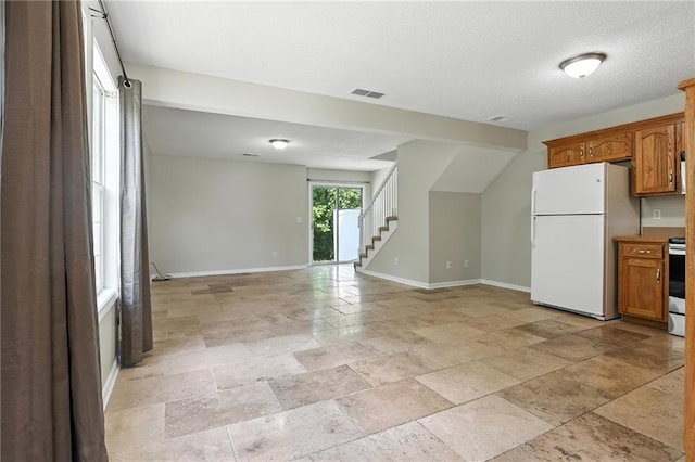 1501 SW Shelby Dr, Lees Summit, MO 64081 - kitchen with freestanding refrigerator, brown cabinets, stone tile flooring, open floor plan, and a textured ceiling