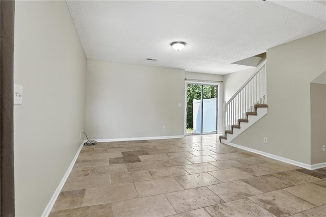 1501 SW Shelby Dr, Lees Summit, MO 64081 - unfurnished room with stairway, a textured ceiling, and stone tile floors