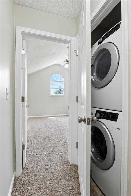 1501 SW Shelby Dr, Lees Summit, MO 64081 - laundry room with stacked washing machine and dryer, carpet floors, a textured ceiling, and ceiling fan
