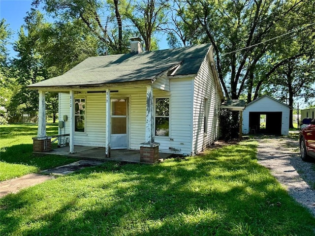 810 Center St, Pleasanton, KS 66075 - bungalow featuring a front yard, covered porch, a chimney, and an outbuilding