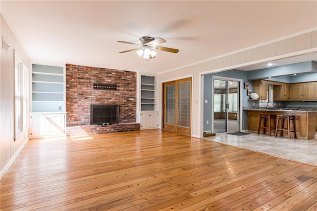 8224 Linden Dr, Prairie Village, KS 66208 - unfurnished living room featuring built in features, light wood-type flooring, ceiling fan, a fireplace, and ornamental molding