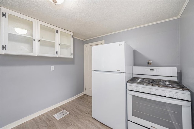 221 S High St, Independence, MO 64054 - kitchen featuring white appliances, light wood finished floors, ornamental molding, a textured ceiling, and glass insert cabinets