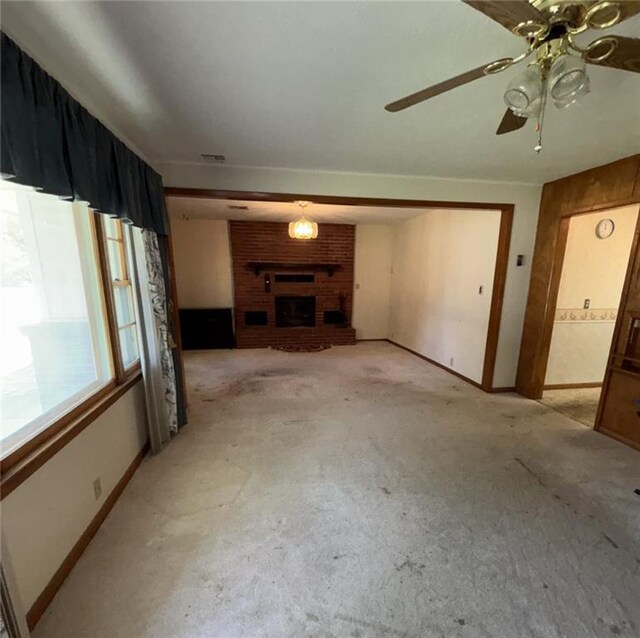 704 S Allen Ave, Chanute, KS 66720 - unfurnished living room with a brick fireplace, ceiling fan, and light colored carpet