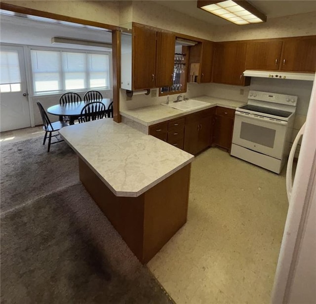 704 S Allen Ave, Chanute, KS 66720 - kitchen with white appliances, extractor fan, light countertops, a peninsula, and brown cabinets