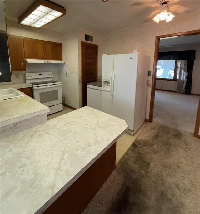 704 S Allen Ave, Chanute, KS 66720 - kitchen featuring white appliances, under cabinet range hood, light countertops, ceiling fan, and brown cabinetry