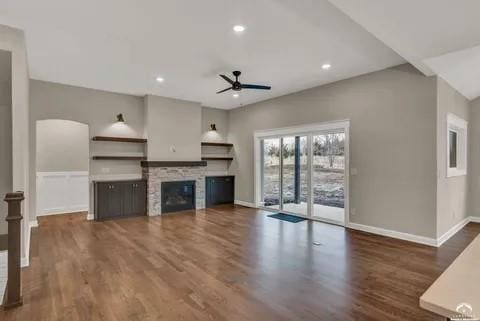 25446 W 91st Ter, Lenexa, KS 66227 - unfurnished living room featuring ceiling fan, wood finished floors, a stone fireplace, recessed lighting, and arched walkways