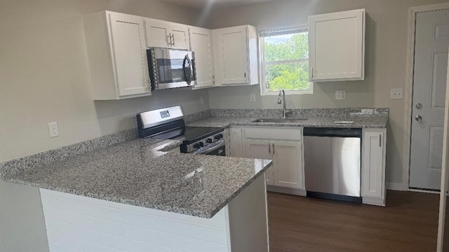 1106 S Mitchell St, Warrensburg, MO 64093 - kitchen with stainless steel appliances, light stone counters, a peninsula, white cabinetry, and dark wood-type flooring