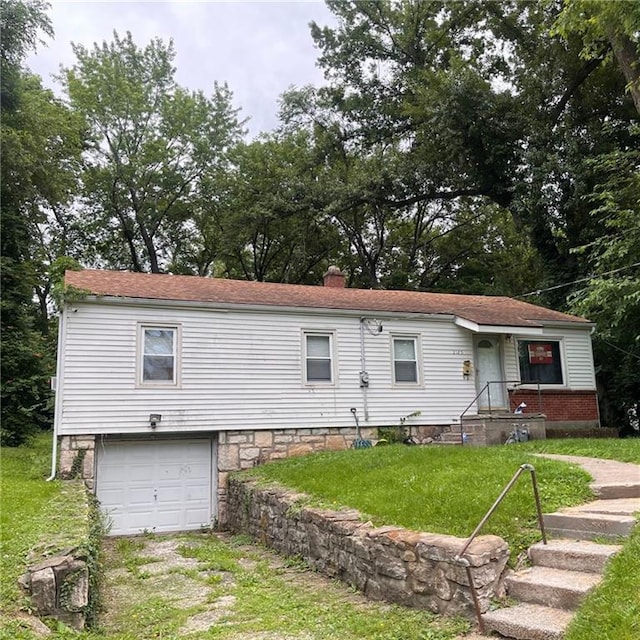 2125 N 45th St, Kansas City, KS 66104 - back of property featuring an attached garage, a lawn, driveway, and a chimney