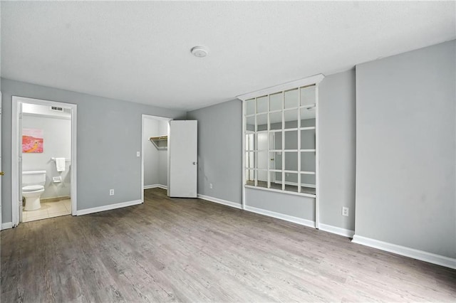 12704 W 110th Ter, Overland Park, KS 66210 - unfurnished bedroom featuring wood finished floors, a spacious closet, and connected bathroom